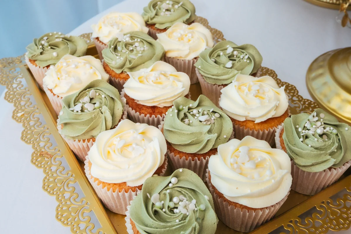 Cupcakes iced in white and sage on a gold tray, from the club kitchen