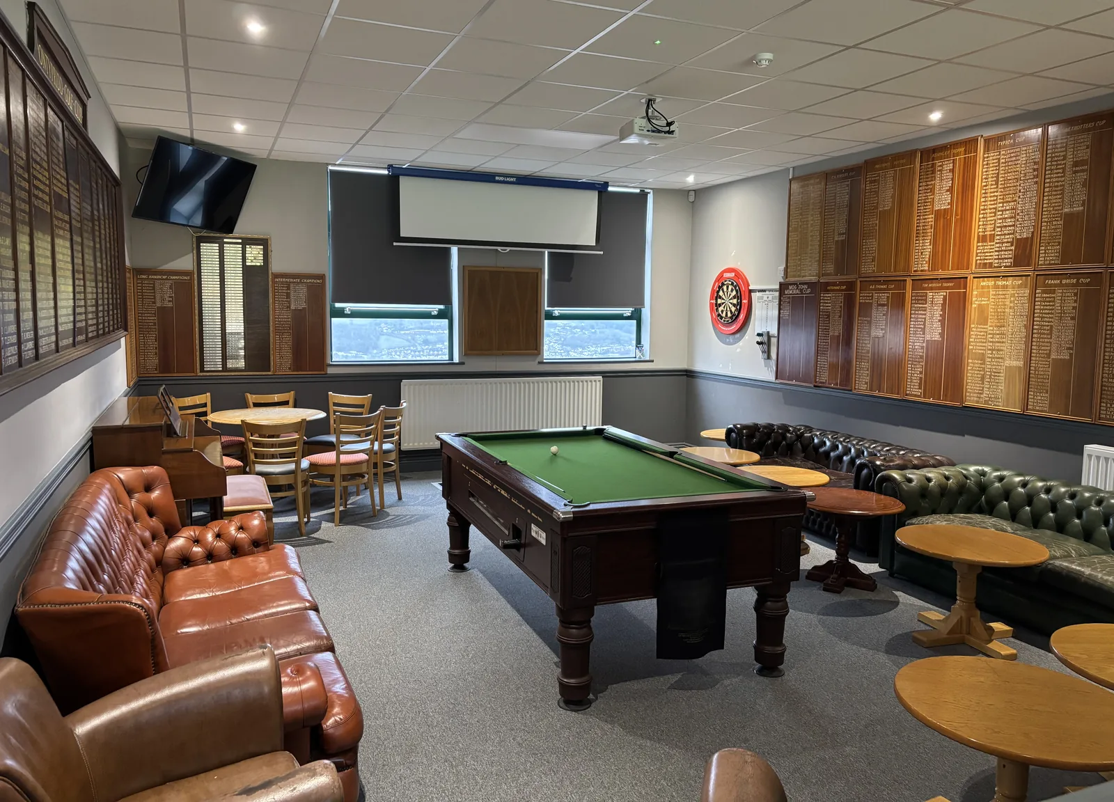 The members' lounge with two walls of honours boards, a dartboard, the pool table and leather chesterfields, the valley visible through the window