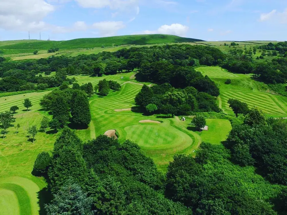 Aerial photograph of Pontypridd Golf Club: striped fairways and greens wrapped in mature trees, with hills rising behind