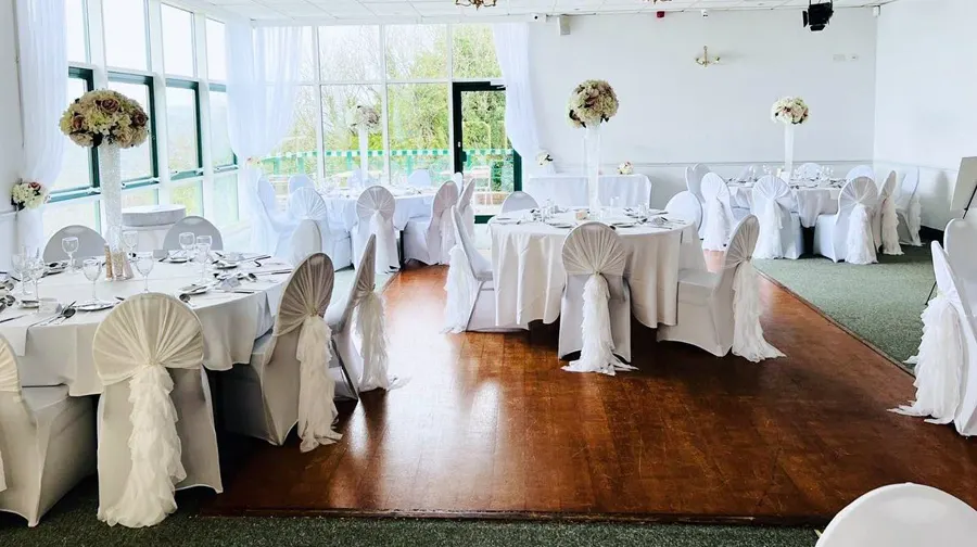 The function room dressed in white with floor-to-ceiling windows over the trees