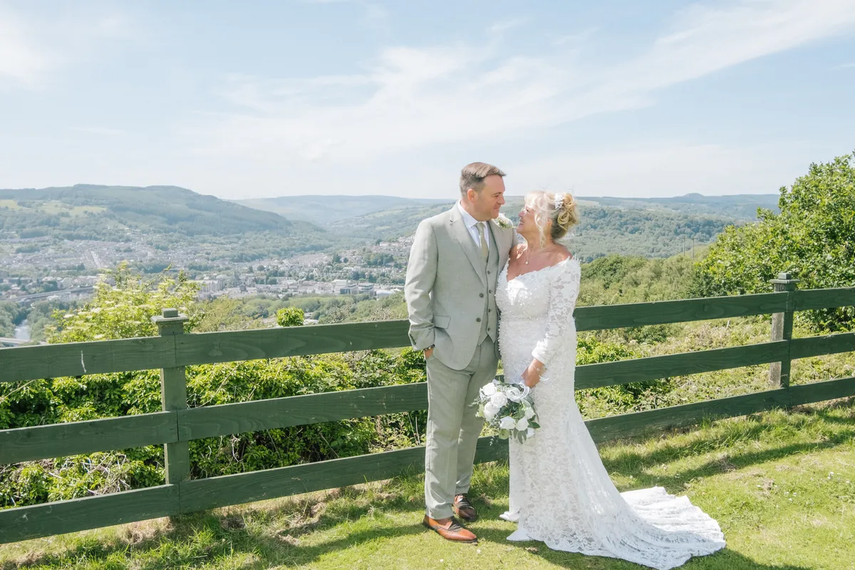 A couple on their wedding day at the clubhouse fence, the whole valley spread out below them